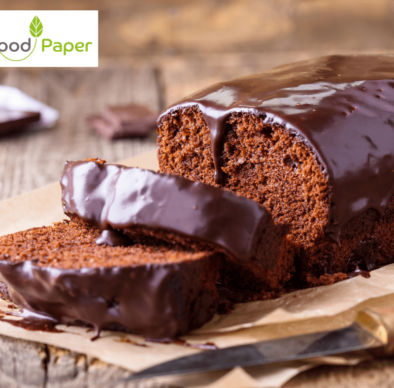Freshly sliced chocolate loaf cake topped with glossy icing, served on Food Paper parchment with brand logo watermark.