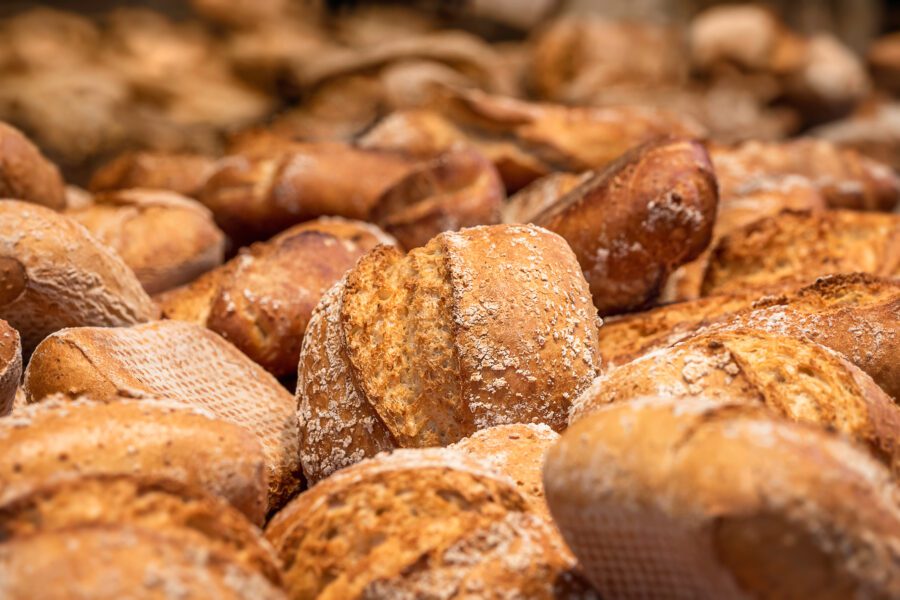 Golden rustic bread rolls with a crisp crust and flour dusting, freshly baked and displayed in a UK bakery.