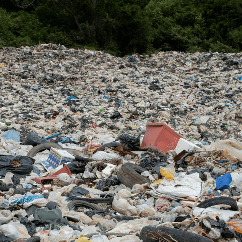 Large landfill site overflowing with plastic waste, bags, and rubbish, illustrating pollution and environmental challenges.