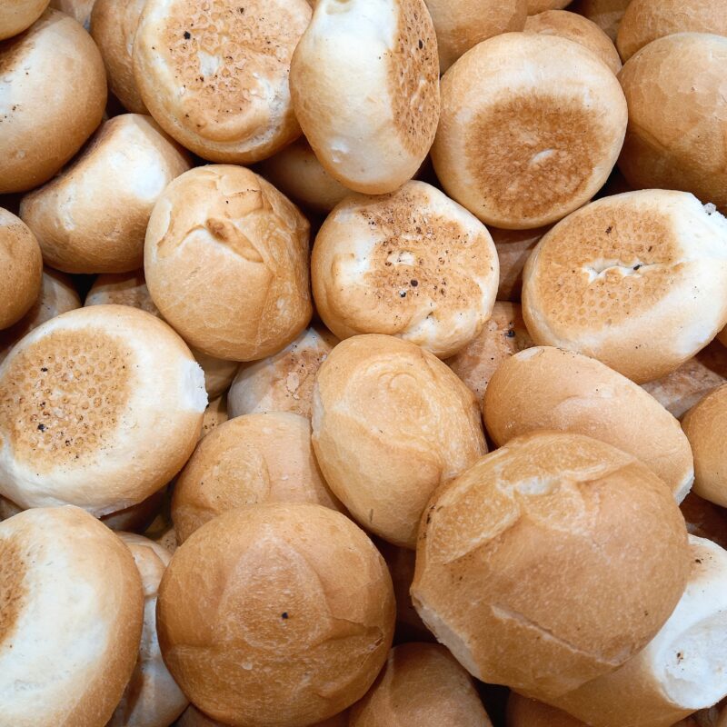 Pile of freshly baked bread rolls with golden brown crusts, soft centres, and rustic texture, ideal for bakery or food display.