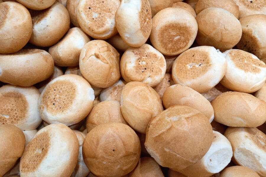 Pile of freshly baked bread rolls with golden brown crusts, soft centres, and rustic texture, ideal for bakery or food display.